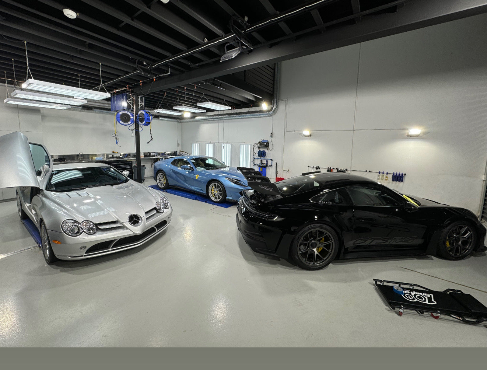 Three supercars in the Alpha Details workshop - Mercedes SLR McLaren, blue Ferrari and black Porsche GT3 RS