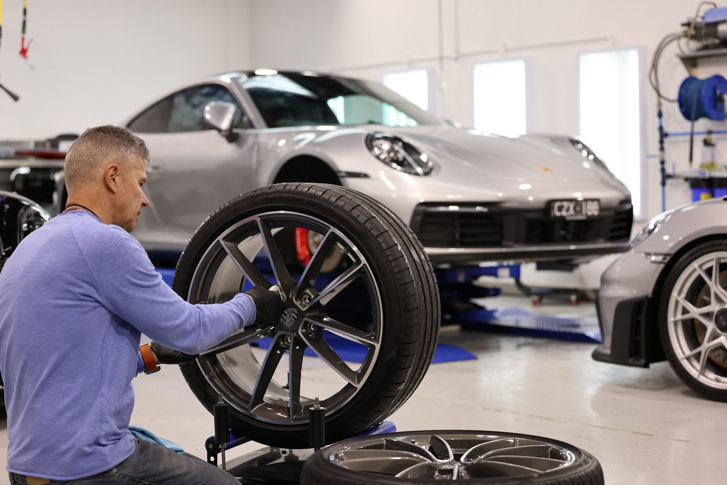 Paolo Recinella cleaning wheels on a Porsche 911 in the Alpha Details workshop, Heidelberg West Melbourne