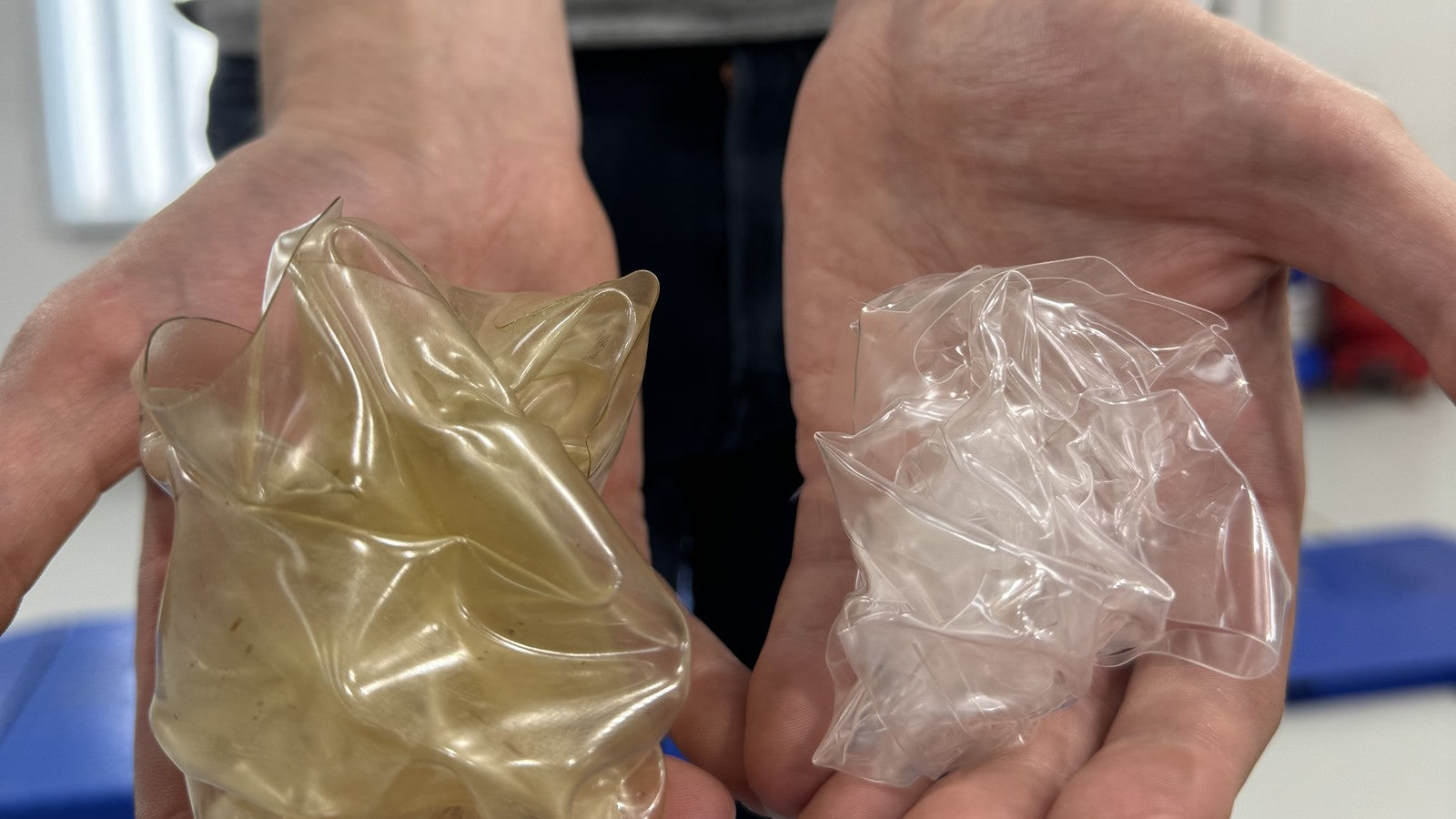 Two hands holding removed paint protection film — the left sheet yellowed from UV degradation, the right still optically clear