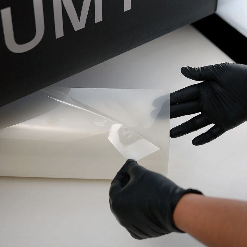 Installer handling Feynlab PPF Flex film demonstrating flexibility and stretch for conformable paint protection