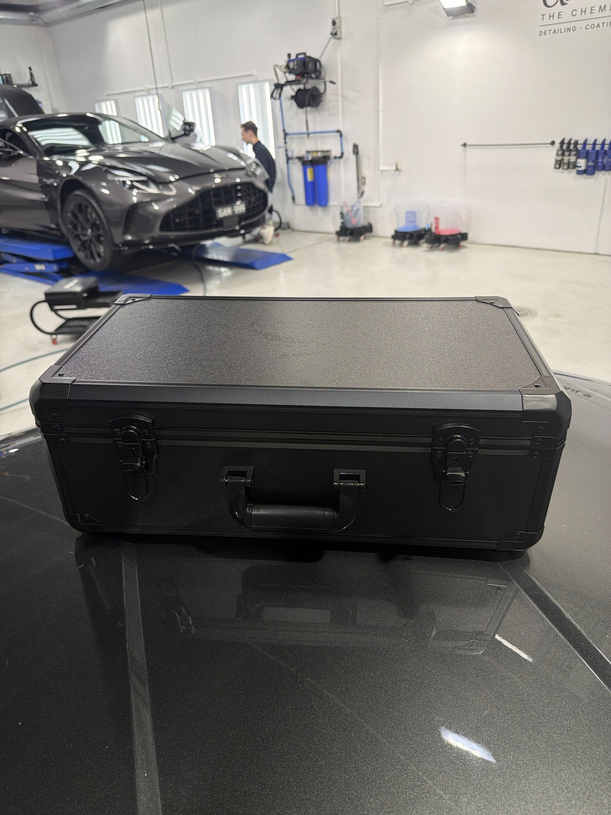 Carton The Black Suit Edition flight case closed, on an Aston Martin at the Alpha Details detailing studio in Heidelberg West