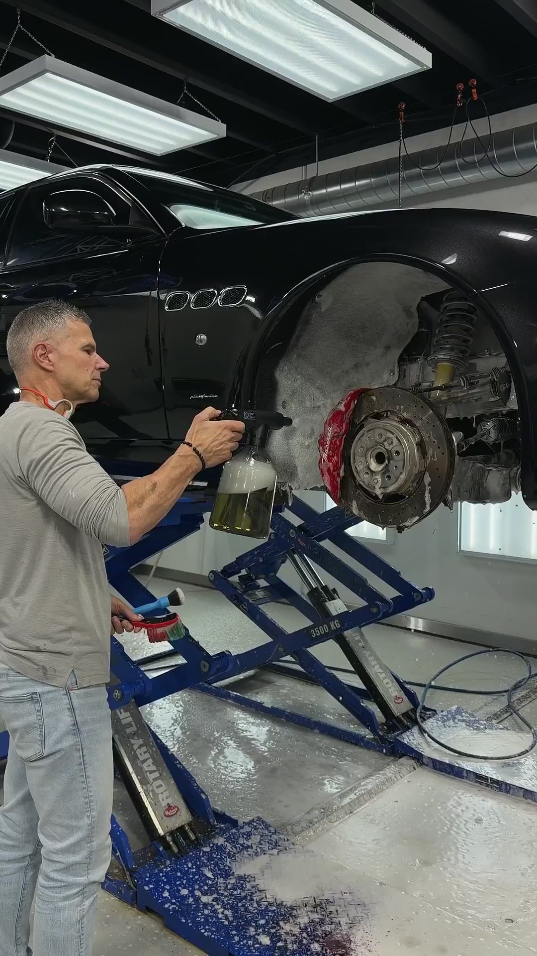 Carton EP.03 cordless electric sprayer in action — applying Maniac Wheel & Tyre Cleaner at 1:5 on a Maserati wheel